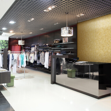 A golden metallic wall panel in a clothing store interior. The panel creates a luxurious backdrop for the clothing displays and gives the space an elegant feel.