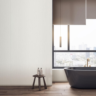 Baño moderno con una bañera negra independiente, un taburete de madera con dos botellas y una gran ventana con vistas a la ciudad. La pared detrás de la bañera está revestida con paneles de madera blancos.