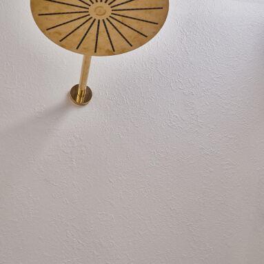 Primer plano de una pared de hormigón con un cabezal de ducha dorado de superficie texturizada.