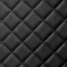 Vista detallada del panel de pared de cuero negro con patrón bordado de diamantes.