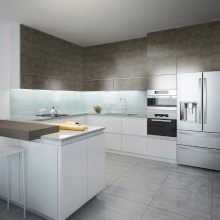 Una cocina moderna con armarios blancos y una pared de piedra detrás de la encimera. En el centro de la cocina hay una gran isla con una barra, y un refrigerador y un horno de acero inoxidable están ubicados en la pared.