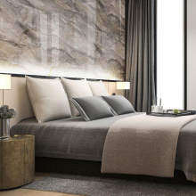 Dormitorio luminoso con una cama grande, una mesita de noche y una ventana con cortinas. La pared detrás de la cama está revestida con un panel de pared con efecto piedra, lo que aporta elegancia al interior.