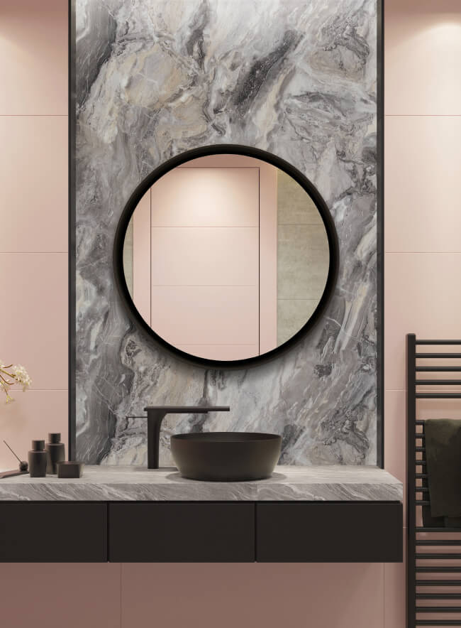 Un baño espacioso con un gran espejo redondo, un mueble de baño negro y una cabina de ducha. Las paredes están recubiertas de un hermoso panel de pared con efecto mármol gris.