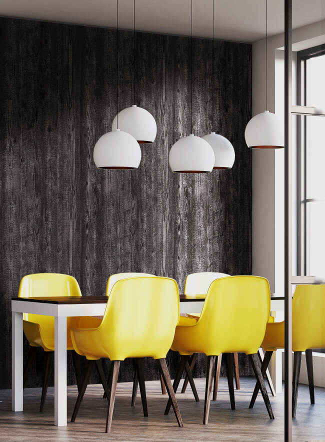 Un comedor moderno con un panel de pared de madera oscura, un suelo a cuadros en blanco y negro y seis sillas amarillas alrededor de una mesa de comedor. Tres lámparas colgantes cuelgan sobre la mesa.