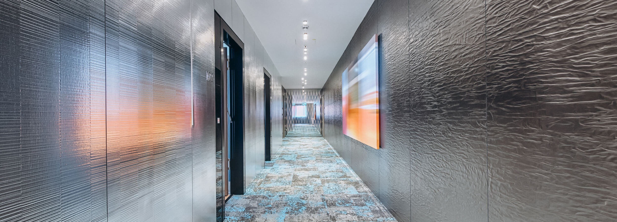 Foto de interior: pasillo con paneles de pared de diseño que imitan el metal, creando un acento texturizado y elegante