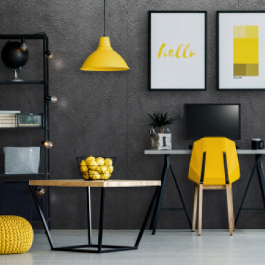 Oficina en casa moderna con paneles de pared de metal texturizado, una cómoda silla de oficina amarilla, una lámpara de escritorio amarilla y un bol de limones en una mesa de centro.