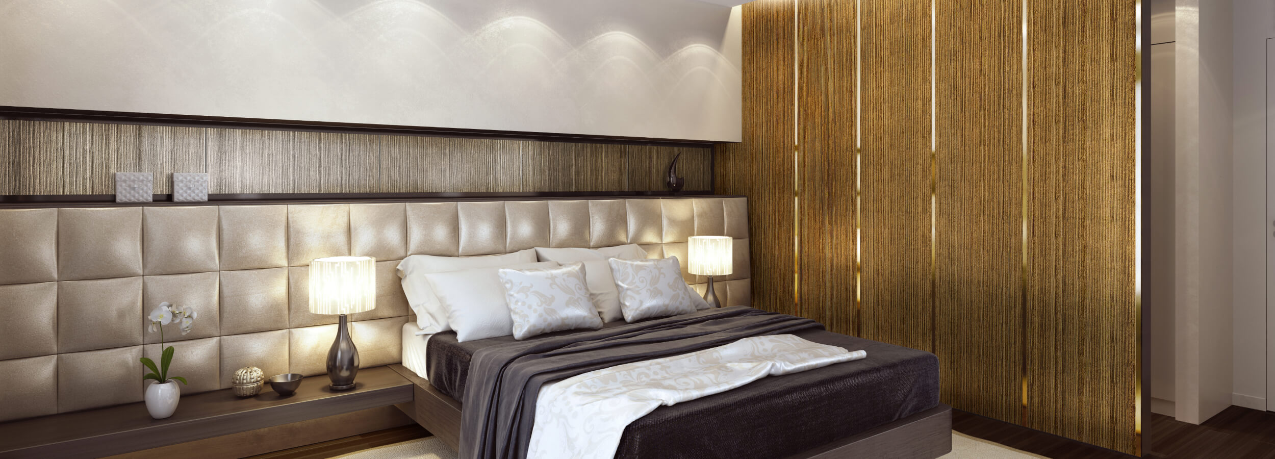 Un dormitorio moderno con un panel de pared de madera detrás de la cama, una cabecera de cuero beige y dos lámparas de noche. La cama está vestida con un edredón gris oscuro y almohadas blancas. Un jarrón de flores se encuentra en la mesita de noche.