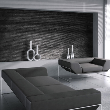 La gama de colores blanco y negro del interior se acentúa con un panel de pared oscuro con textura de madera natural, complementado por un elegante sofá modular y jarrones metálicos.