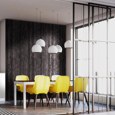 Un comedor moderno con un panel de pared de madera oscura, un suelo a cuadros en blanco y negro y seis sillas amarillas alrededor de una mesa de comedor. Tres lámparas colgantes cuelgan sobre la mesa.