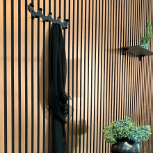 Panneaux acoustiques WallFace à lamelles dans un couloir avec patères et plante d'intérieur