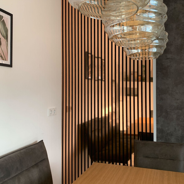 Panneaux acoustiques WallFace à lamelles dans un ton brun chaud dans une salle à manger moderne avec suspension