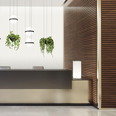 Interni moderni di una hall d'ufficio: una reception in pietra scura, eleganti lampade a sospensione, piante vive in vasi sospesi e una parete accentata con un pannello in legno.